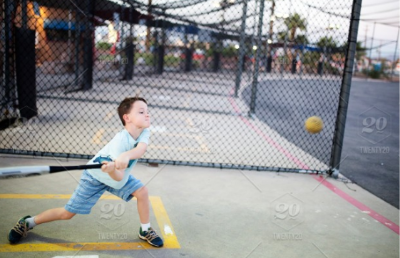 boy swinging a bat at a ball - baseball facilities