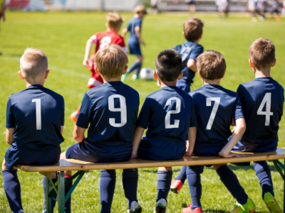 Five youth soccer substitutes on a bench.