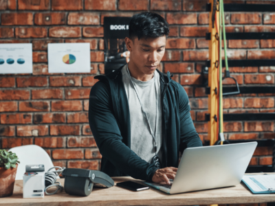 Gym owner standing at desk on laptop.