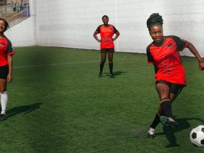 three young black women in red shirts playing soccer